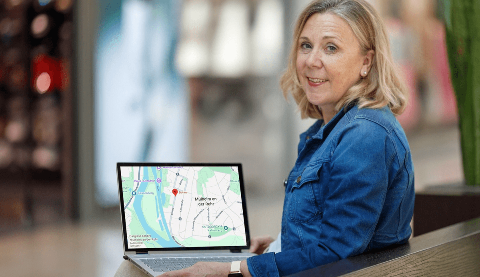 Nicole Bender lächelt in die Kamera, auf ihrem Laptop ist eine Karte von Mülheim an der Ruhr zu sehen